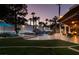 A nighttime view of the gorgeous backyard featuring a sparkling pool, patio, and lush tropical landscaping at 2101 Diamond Bar Dr, Las Vegas, NV 89117