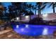 Inviting pool featuring rock waterfalls, colorful lighting, and tropical landscaping at night at 2101 Diamond Bar Dr, Las Vegas, NV 89117