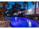 Backyard pool with a waterfall, lush palm trees and ambient lighting for evening enjoyment at 2101 Diamond Bar Dr, Las Vegas, NV 89117