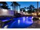 Backyard pool with rock waterfall, lush palm trees and ambient lighting at twilight at 2101 Diamond Bar Dr, Las Vegas, NV 89117