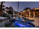 Night view of the backyard pool and jacuzzi with ambient lighting, set amongst rocks and lush greenery at 2101 Diamond Bar Dr, Las Vegas, NV 89117