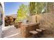 Custom stone outdoor grill area with built-in seating and counter space overlooking the backyard at 25 Blue Valley Dr, Henderson, NV 89002