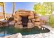 Pool featuring custom rock grotto with hidden seating area and tropical landscaping at 25 Blue Valley Dr, Henderson, NV 89002