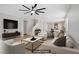 Bright, staged living room with modern ceiling fan, television and comfortable seating with eat-in kitchen in background at 2628 Ferrara St, Henderson, NV 89044