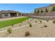 Expansive backyard featuring artificial turf, stone landscaping, and a retaining wall with privacy plants at 281 Gandara St, Las Vegas, NV 89138