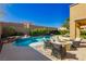 This beautiful yard features a pool and spa area, lounge furniture, a fire pit and mountain views at 29 Blue Valley Dr, Henderson, NV 89002