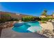 A gorgeous backyard features a beautiful blue pool with a spa, rock features, mature landscaping, and ample patio space at 29 Blue Valley Dr, Henderson, NV 89002