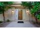 Inviting front entrance with a solid wood door, sidelights, and sconces, framed by lush greenery at 5125 Turnberry Ln, Las Vegas, NV 89113
