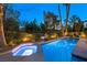 Twilight shot of a sparkling pool and connected hot tub surrounded by lush landscaping at 5125 Turnberry Ln, Las Vegas, NV 89113