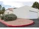 Exterior view of home with red gravel landscaping, well-maintained bushes and garage at 5400 Tassara Way # 106, Las Vegas, NV 89108
