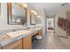 Bathroom featuring double sinks with framed mirrors and granite countertops, with a view into the main bedroom at 6999 Stone Meadows Ave, Las Vegas, NV 89142