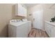 Bright laundry room with white cabinets, appliances, and wood-look flooring at 6999 Stone Meadows Ave, Las Vegas, NV 89142