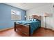 Bedroom with wood floor, blue accent wall, with complementary lamps, linens, and window to the backyard at 7400 Amigo St, Las Vegas, NV 89123