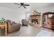 Spacious living room featuring wood-look tile floors, brick fireplace, ceiling fan, and cozy leather furniture at 7400 Amigo St, Las Vegas, NV 89123