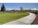 Concrete walking path through a park with green grass and desert landscaping at 7931 Mineral Peak St, Las Vegas, NV 89166