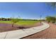 Concrete walking path through a green community park with trees and landscaping at 7931 Mineral Peak St, Las Vegas, NV 89166