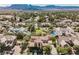 Aerial view showcases neighborhood homes with pools, lush landscaping, and a park surrounded by mountains at 7947 Lookout Rock Cir, Las Vegas, NV 89129