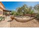 Manicured backyard featuring mature trees, a pergola, and a stone-lined fire pit at 7947 Lookout Rock Cir, Las Vegas, NV 89129