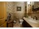 Charming bathroom featuring decorative wallpaper, an ornate mirror, and an antique-style vanity with marble countertop at 7947 Lookout Rock Cir, Las Vegas, NV 89129