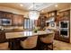 This kitchen showcases a large island with seating, wooden cabinetry, stainless steel appliances, and tiled flooring at 7947 Lookout Rock Cir, Las Vegas, NV 89129