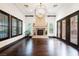 Spacious living room featuring hardwood floors, a stone fireplace, large windows, and elegant lighting at 7947 Lookout Rock Cir, Las Vegas, NV 89129