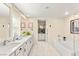 Bright bathroom featuring double sinks, white cabinets, a large mirror, and a soaking tub at 812 Stannard Ct, Henderson, NV 89052