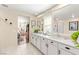 Elegant bathroom featuring double sinks, white cabinets, a large mirror, and an open doorway to the bedroom at 812 Stannard Ct, Henderson, NV 89052
