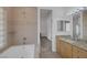Bathroom showcasing tile work, granite counters, wood cabinets, tub, and lots of natural light at 8130 Cassian Ct, Las Vegas, NV 89129