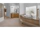 Luxurious bathroom featuring a soaking tub, a glass block wall, and a marble-tiled surround at 8130 Cassian Ct, Las Vegas, NV 89129