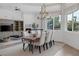 Elegant dining room featuring a modern table, chandelier, large windows, and views of the backyard at 8130 Cassian Ct, Las Vegas, NV 89129