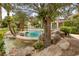 Picturesque pool area surrounded by lush greenery, mature trees, and custom rock details at 8130 Cassian Ct, Las Vegas, NV 89129