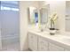 Bright bathroom featuring a dual sink vanity with tile counters and framed mirrors plus a full bathtub at 8714 Las Posas Ave, Las Vegas, NV 89147