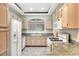 Functional kitchen featuring tile floors, granite counters, white appliances, and bright window lighting at 8725 Red Rio Dr # 203, Las Vegas, NV 89128