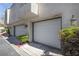 Exterior shot of garage doors with green bushes and an exterior light at 8932 Antioch Way, Las Vegas, NV 89117