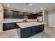 Modern kitchen with dark cabinets, stainless steel appliances, a large center island and stylish gray tile flooring at 9239 Albus Hills Ave, Las Vegas, NV 89143