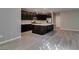 Modern kitchen boasts dark cabinetry, stainless steel appliances, a spacious island, and stylish gray wood-look tile flooring at 9239 Albus Hills Ave, Las Vegas, NV 89143