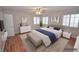 Staged bedroom with hardwood floors, two windows with shutters, and modern furniture at 9408 Amber Valley Ln, Las Vegas, NV 89134