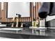 Close-up of a modern sink featuring a gold faucet, black countertop, and wooden accent wall at 9513 Villa Ridge Dr, Las Vegas, NV 89134