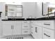 Bathroom featuring dual sinks, black countertops, and white cabinets at 9513 Villa Ridge Dr, Las Vegas, NV 89134