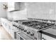 Close up of range with double oven, black countertop and tile backsplash at 9513 Villa Ridge Dr, Las Vegas, NV 89134