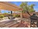 Backyard patio with pergola cover, outdoor dining area, and a grill, all surrounded by mature landscaping at 10791 Silver Lace Ln, Las Vegas, NV 89135