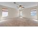 Spacious bedroom with three windows, carpet flooring, and a ceiling fan at 10791 Silver Lace Ln, Las Vegas, NV 89135