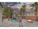 Backyard features a custom pool with rock waterfall, a fire pit, and mature landscaping under a dramatic sky at 11158 Antonine Wall Ct, Las Vegas, NV 89141