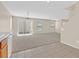 Open-concept living room with neutral carpet adjacent to the kitchen, tile flooring, and sliding glass door at 11934 Wild Chamomile St, Las Vegas, NV 89183