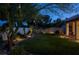Expansive backyard with mature trees, lush green lawn, landscaped borders and ambient lighting for evening enjoyment at 1432 Castle Crest Dr, Las Vegas, NV 89117