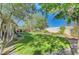 Lush green backyard with manicured lawn, mature trees, and a covered patio ideal for relaxation and entertaining at 1432 Castle Crest Dr, Las Vegas, NV 89117