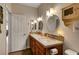 Well-lit bathroom featuring double sinks with decorative backsplash, cabinets, and a view to another room at 1432 Castle Crest Dr, Las Vegas, NV 89117