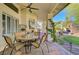Outdoor living area with a covered patio, ceiling fan, stone fireplace, dining table, and lush backyard views at 1432 Castle Crest Dr, Las Vegas, NV 89117