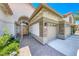 Close-up of the front door with a security gate, brick accents, a beige three-car garage, and brick walkway at 1432 Castle Crest Dr, Las Vegas, NV 89117