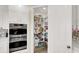Pantry with a stainless steel double oven and white shelving filled with food and storage at 232 Delighted Ave, North Las Vegas, NV 89031